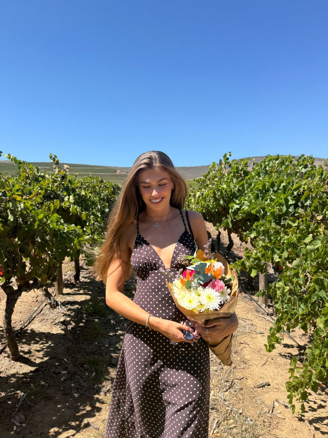 Amie in a vineyard holding flowers